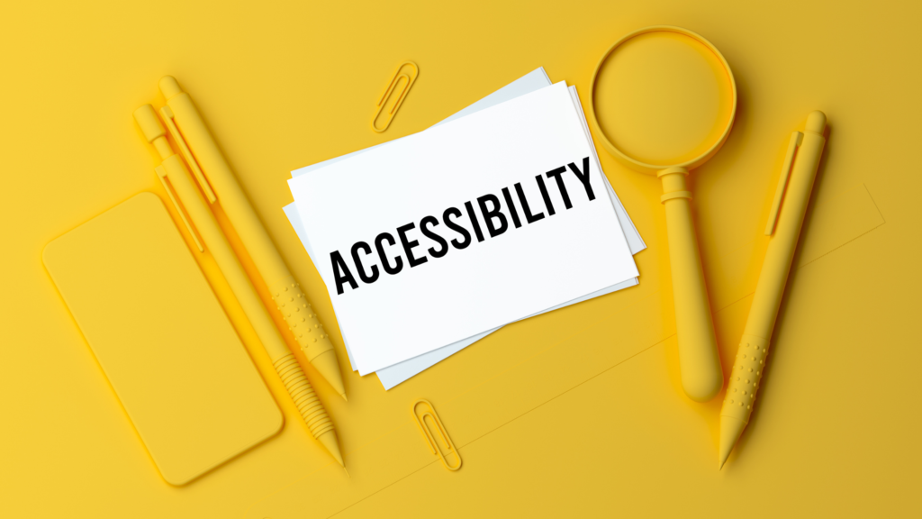 Yellow background with office supplies, pens, phone, paperclips ontop of the paper. White rectangle with words "accessibility" written in black.