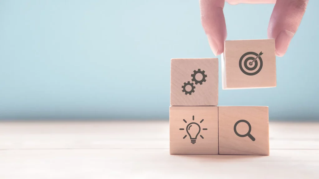 Four wooden blocks with gears, target, lightbulb and magnifying glass