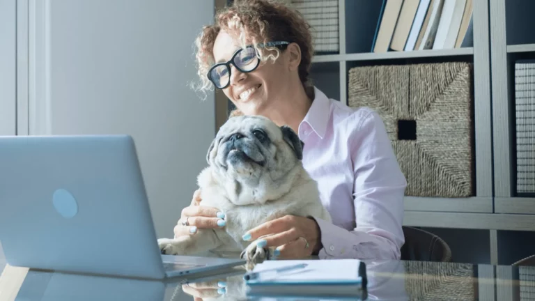 Woman with dog on lap looking at laptop computer